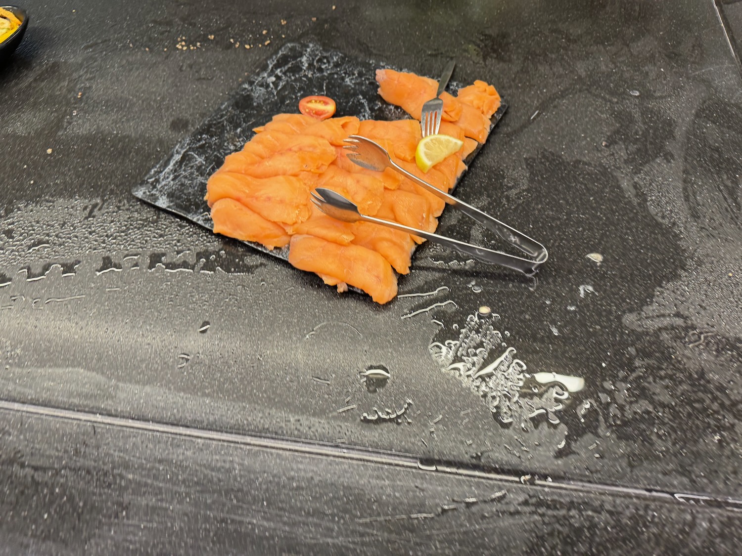 a plate of salmon with forks and lemon slices