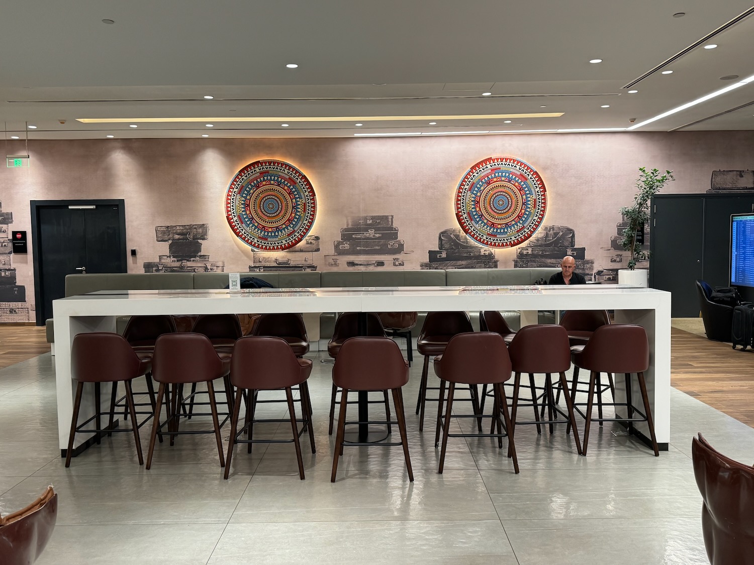 a man sitting at a table in a room with chairs and a wall with a picture of a tank