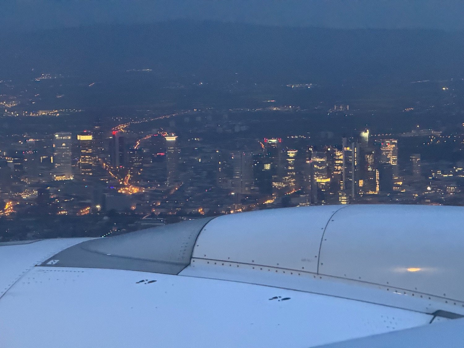 an airplane wing with lights in the background