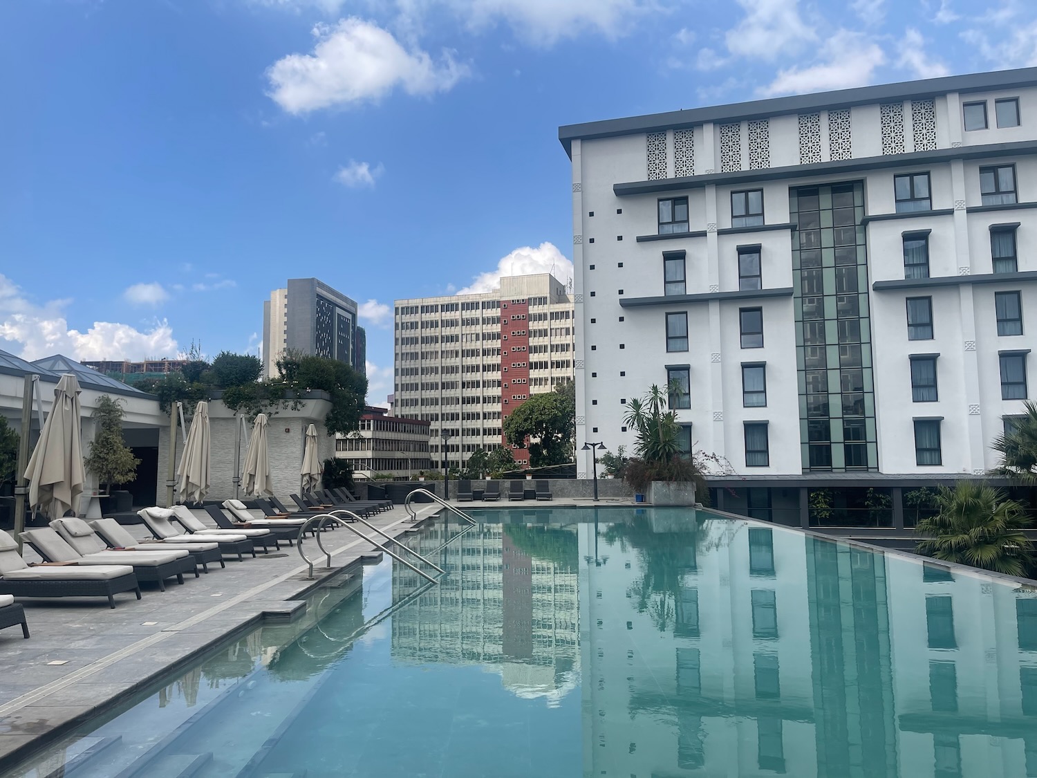 a pool with lounge chairs and a building in the background