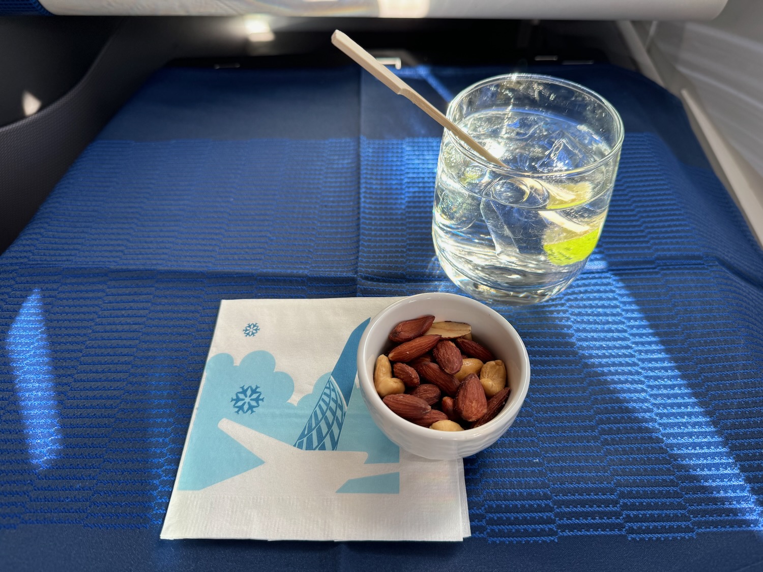 a bowl of nuts and a glass of water on a blue surface