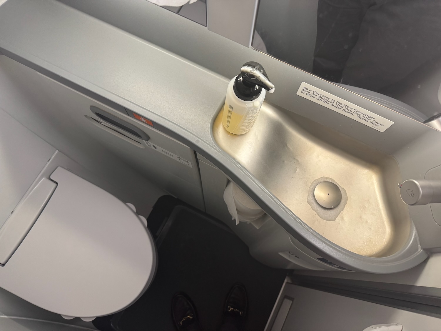 a sink with soap dispenser and toilet