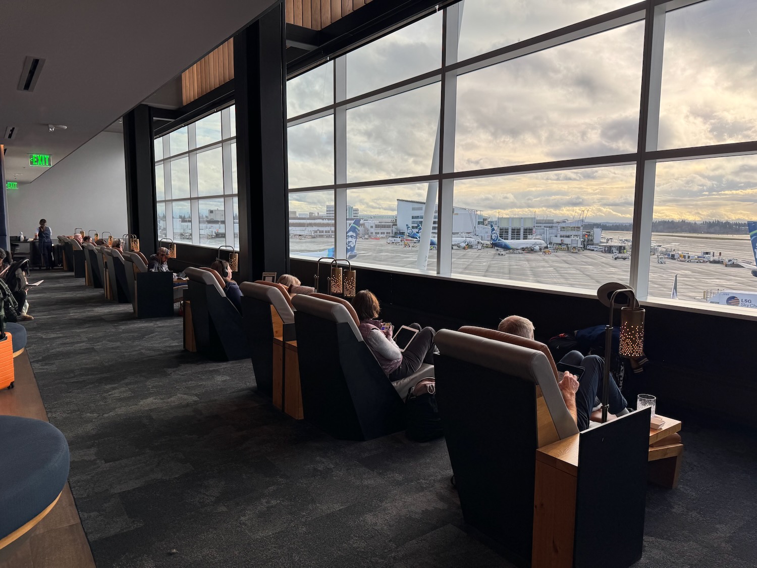people sitting in chairs in a building with large windows