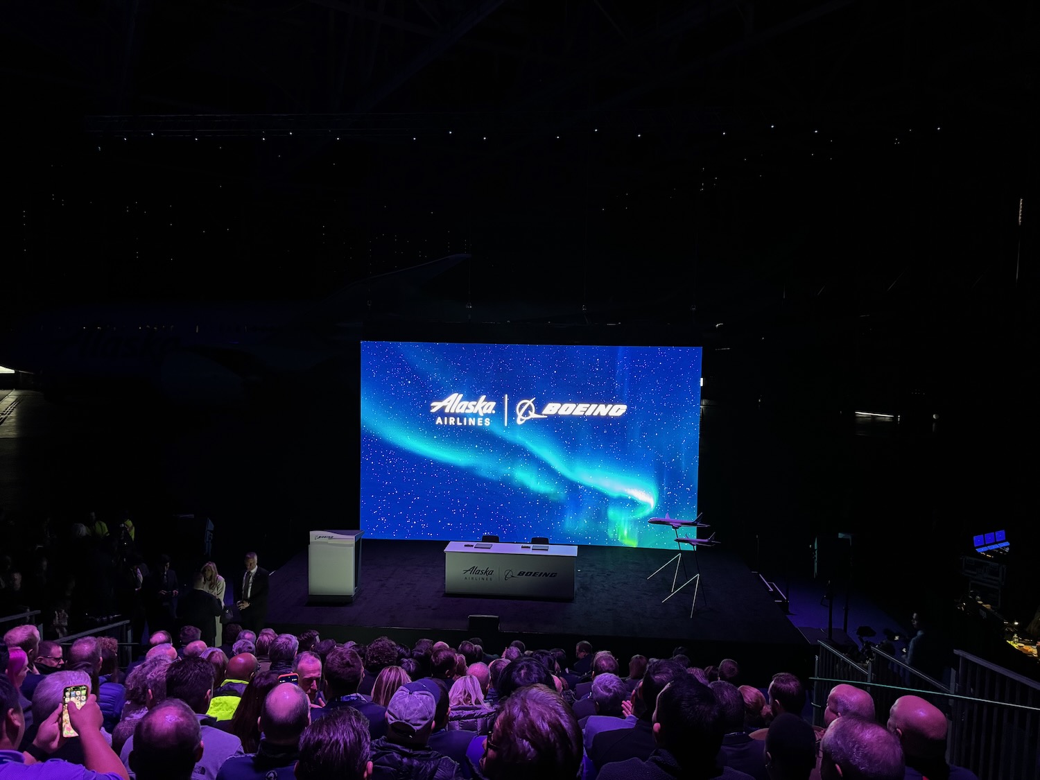 a crowd of people watching a stage with a large screen