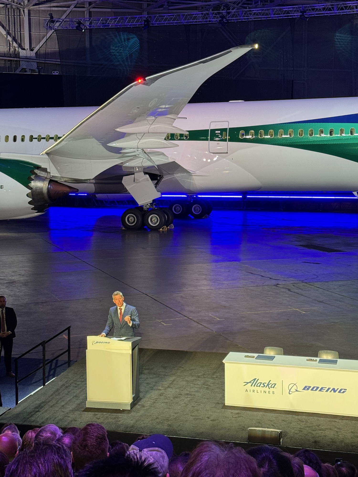 a man standing at a podium in front of an airplane