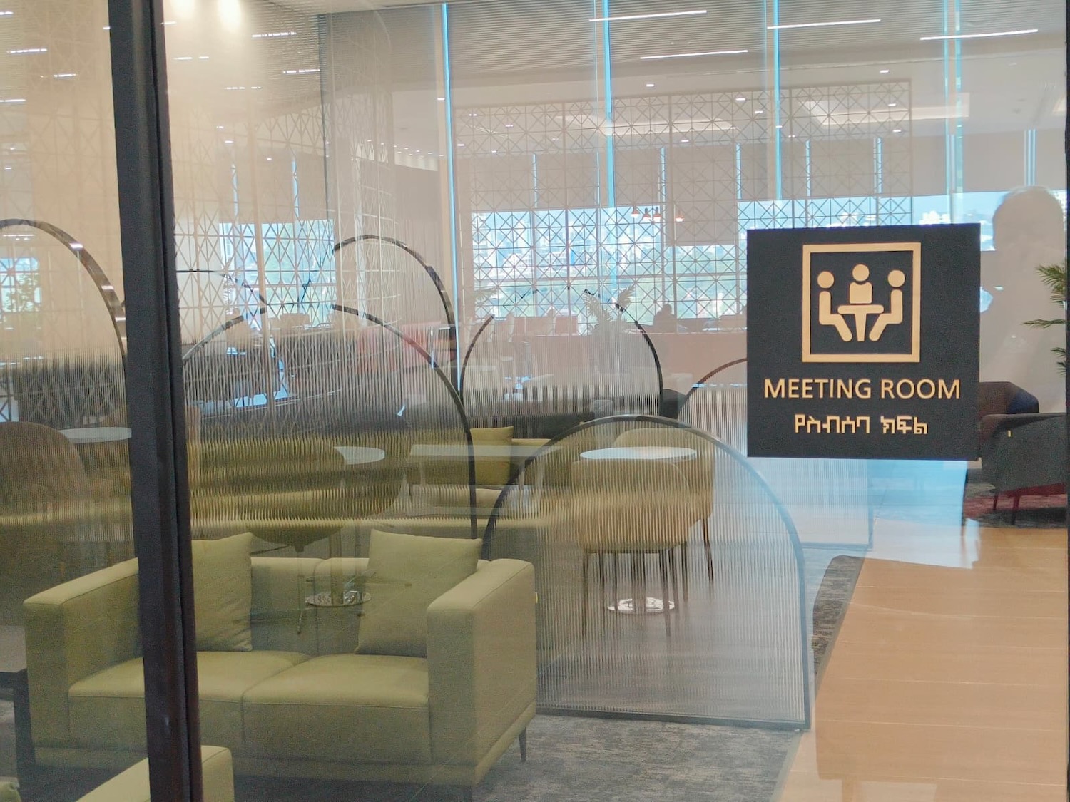 a glass wall with a sign and chairs in the background