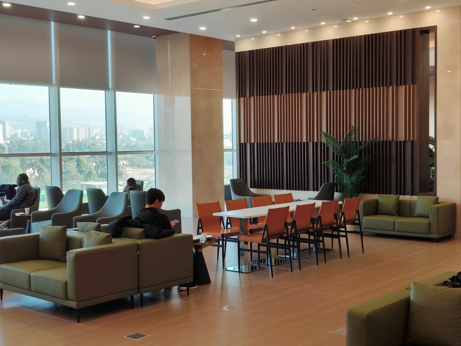 a room with a large window and a man sitting on a couch