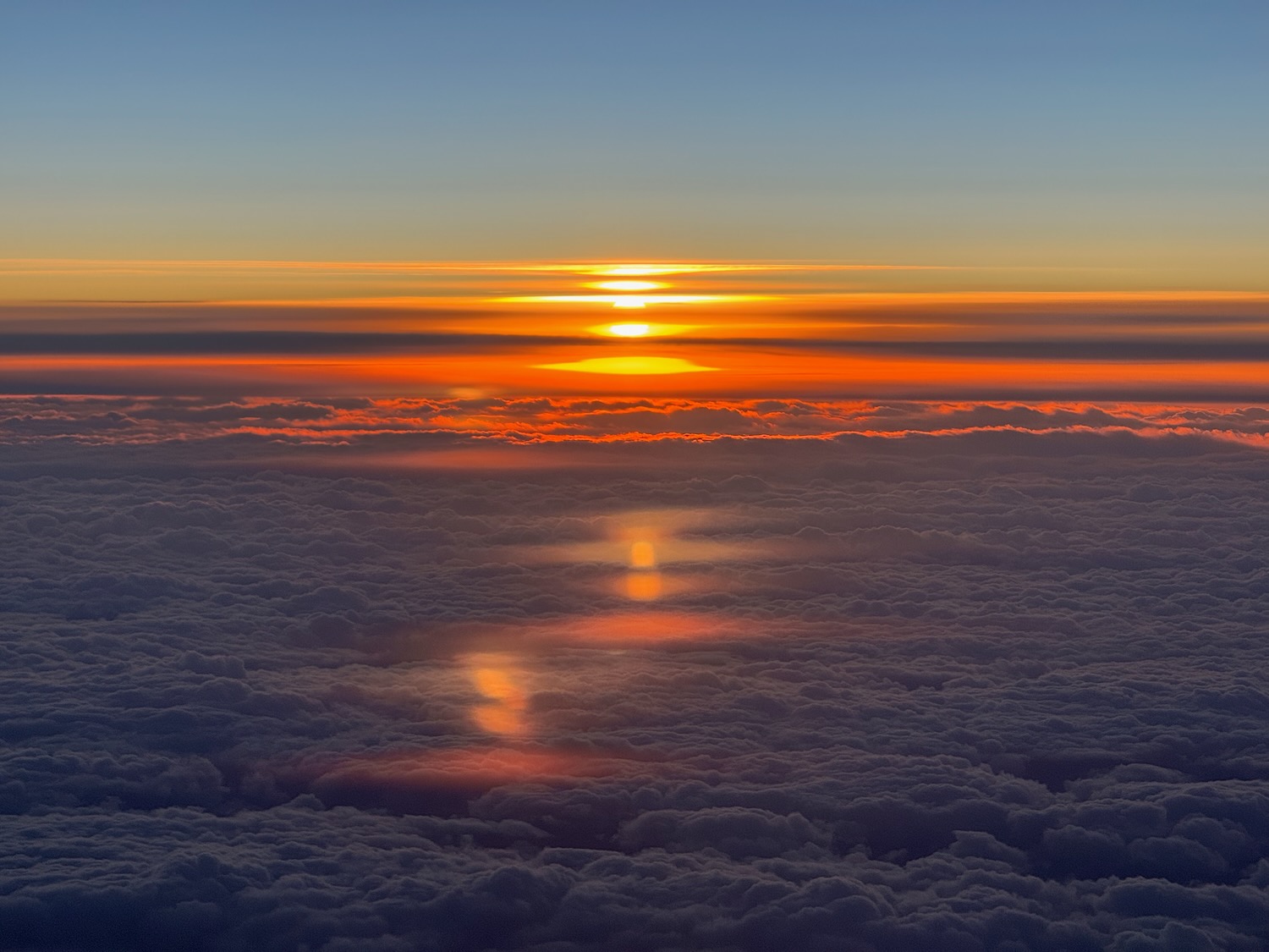 a sunset over clouds and a blue sky