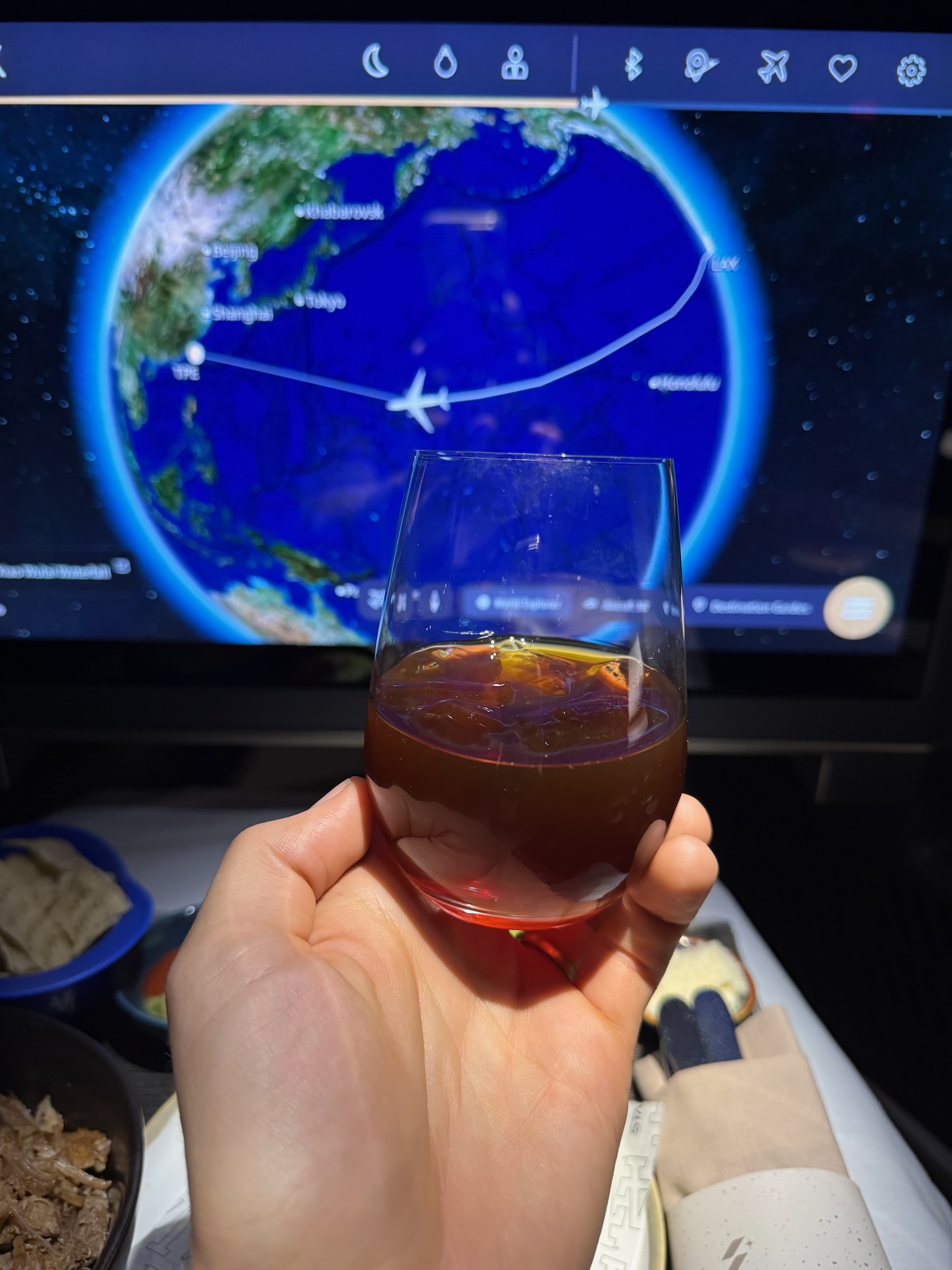 a hand holding a glass of liquid in front of a television screen
