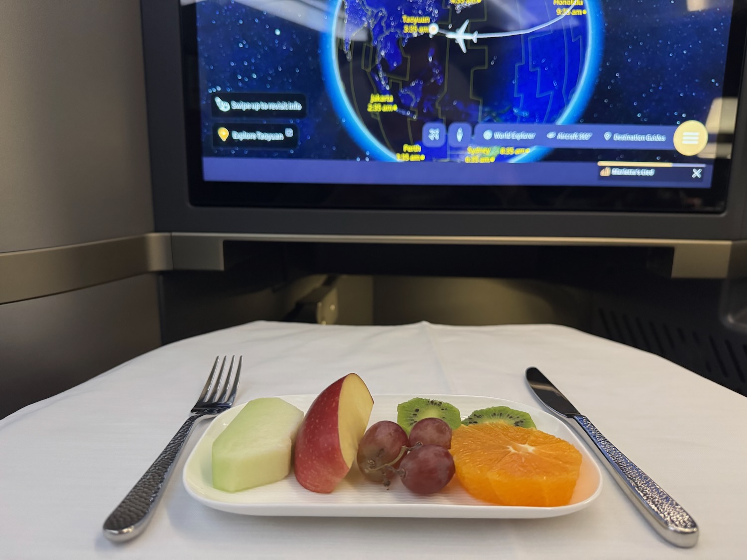 a plate of fruit and a fork on a table with a television