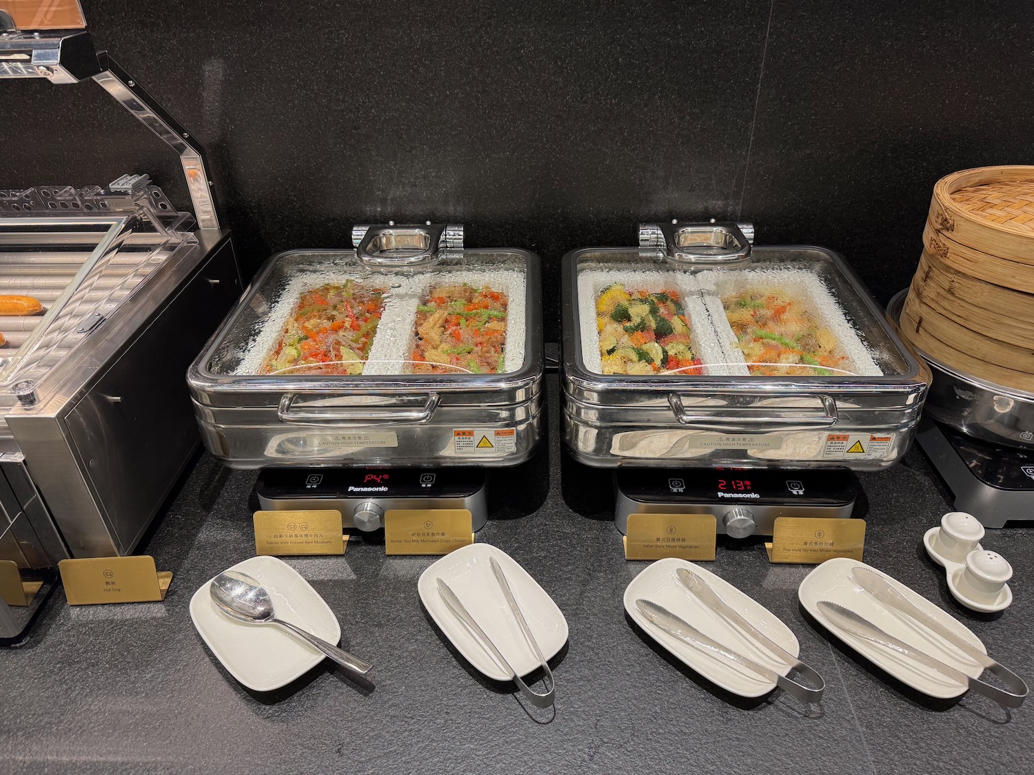 food in a buffet with plates and spoons