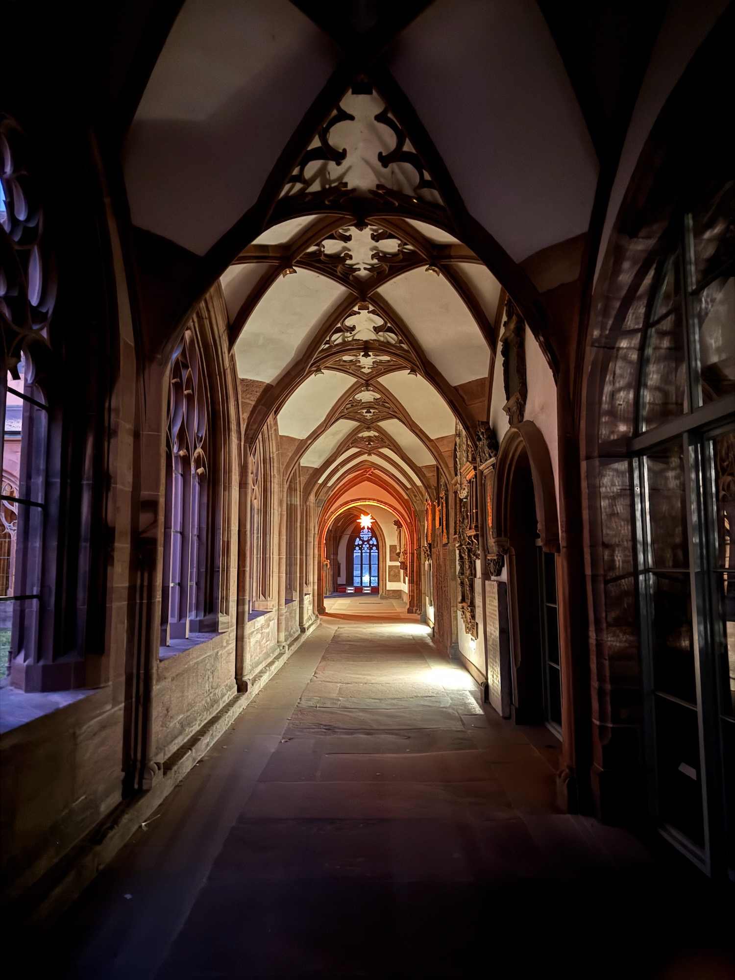 a hallway with arched windows and a stone walkway