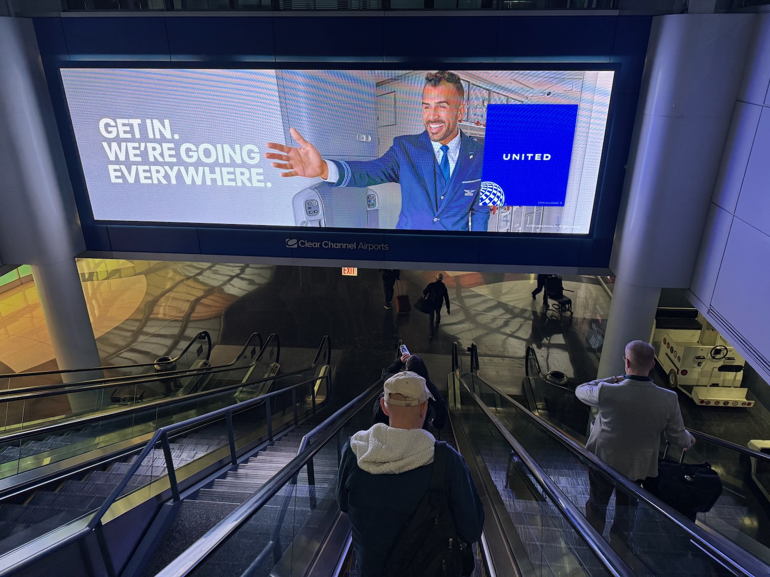 a man standing on escalator and a screen with a man on it