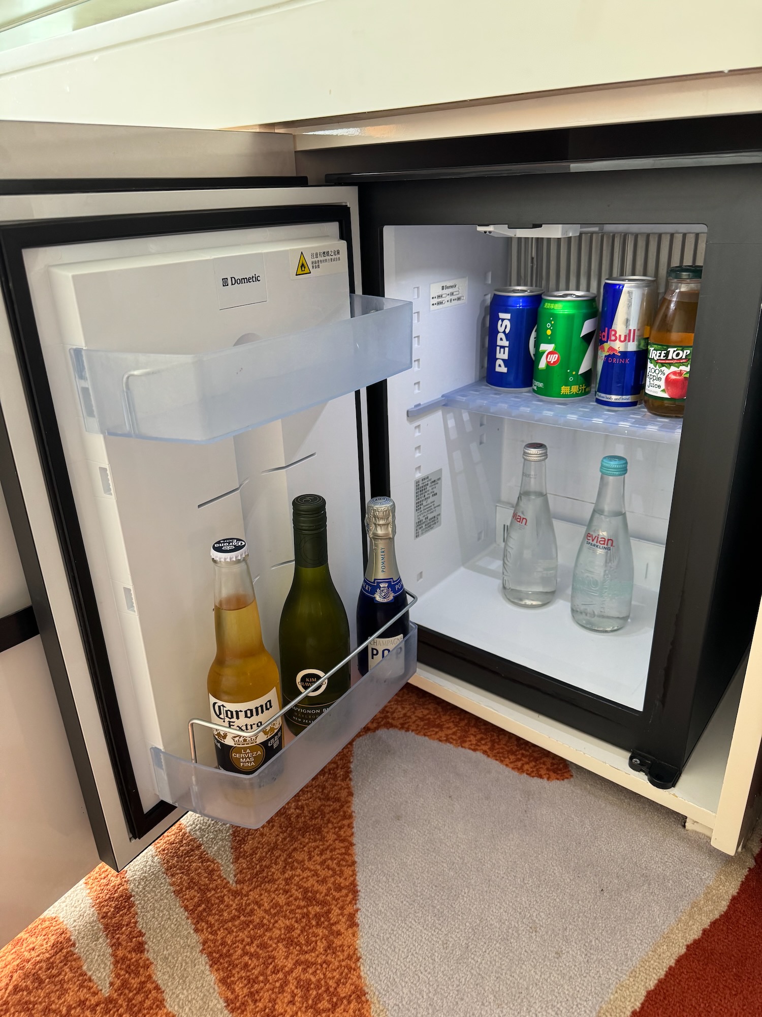 a mini fridge with bottles of beer and cans of soda