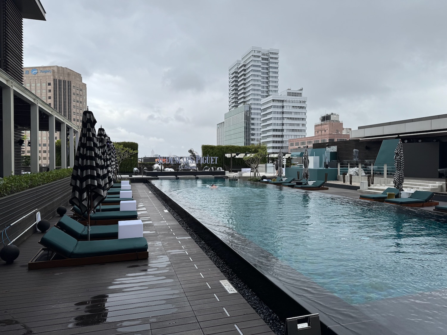 a pool with lounge chairs and umbrellas in a city