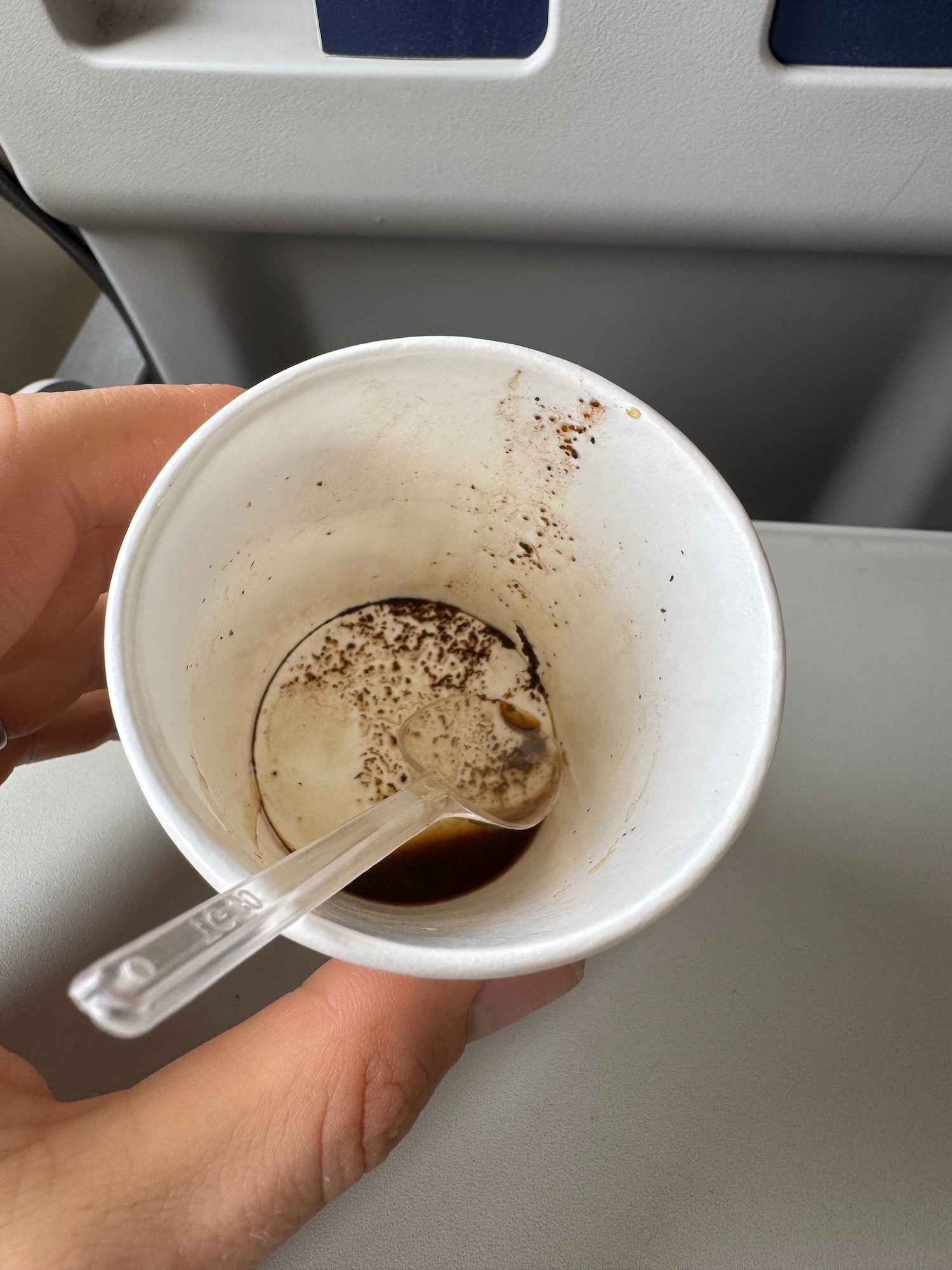 a hand holding a cup with a spoon
