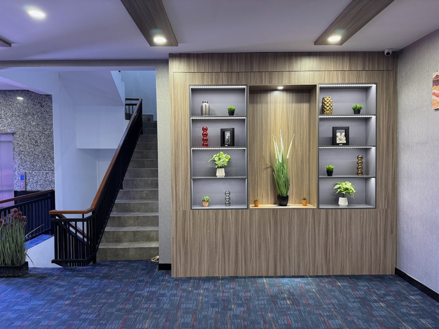 a room with a staircase and shelves with plants