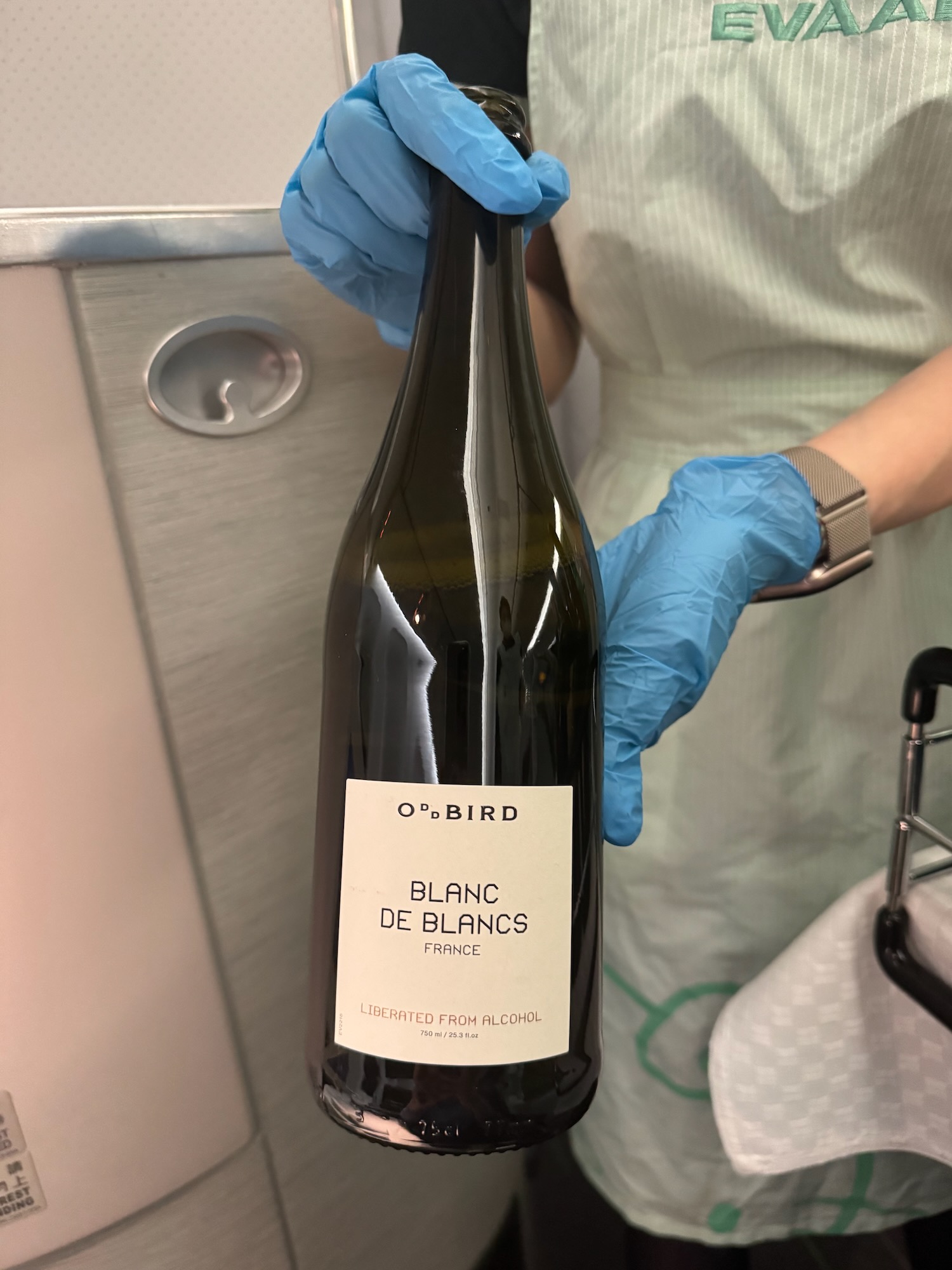 a person wearing gloves holding a bottle of wine