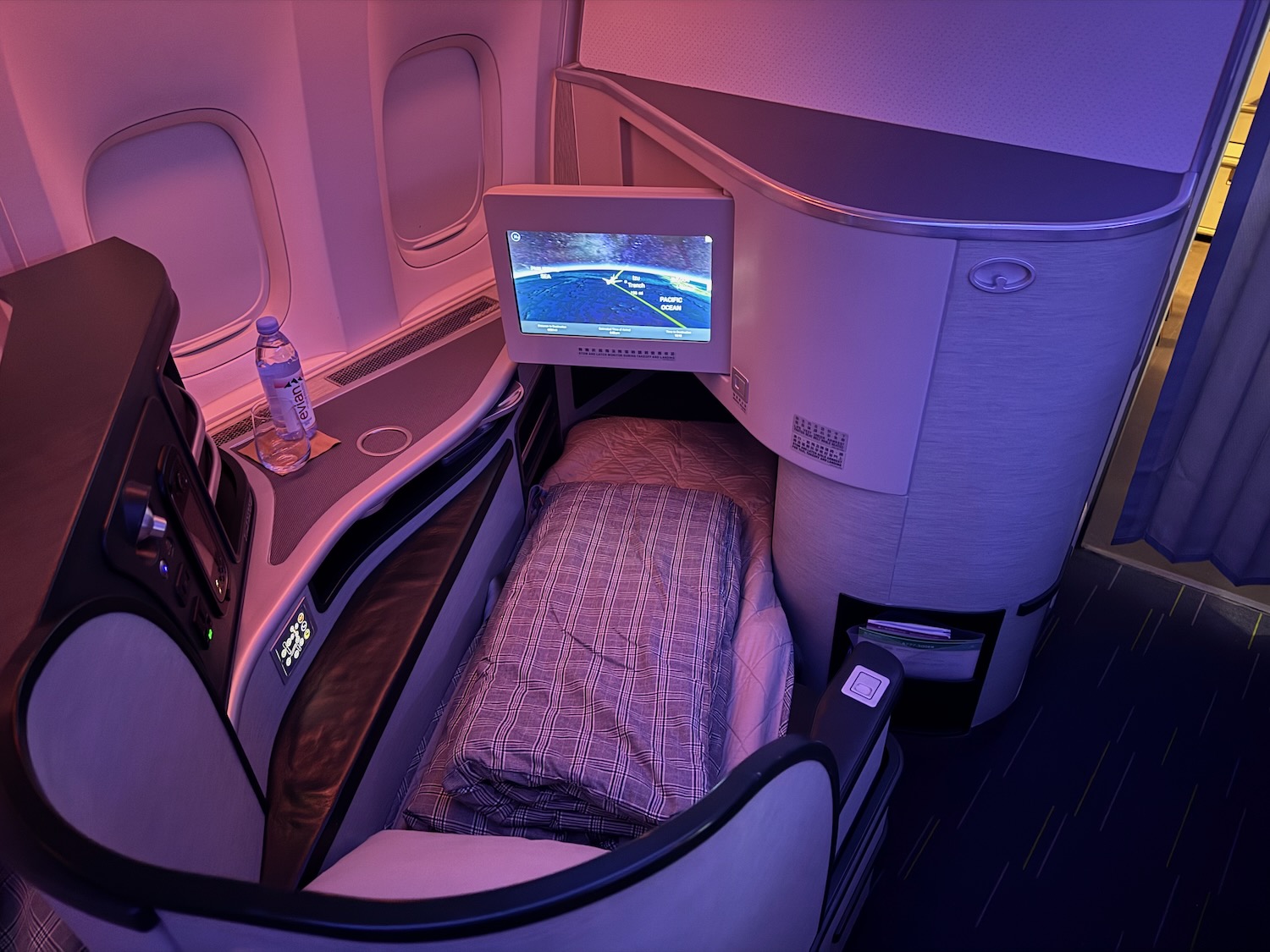 a bed with a monitor in the corner of a plane