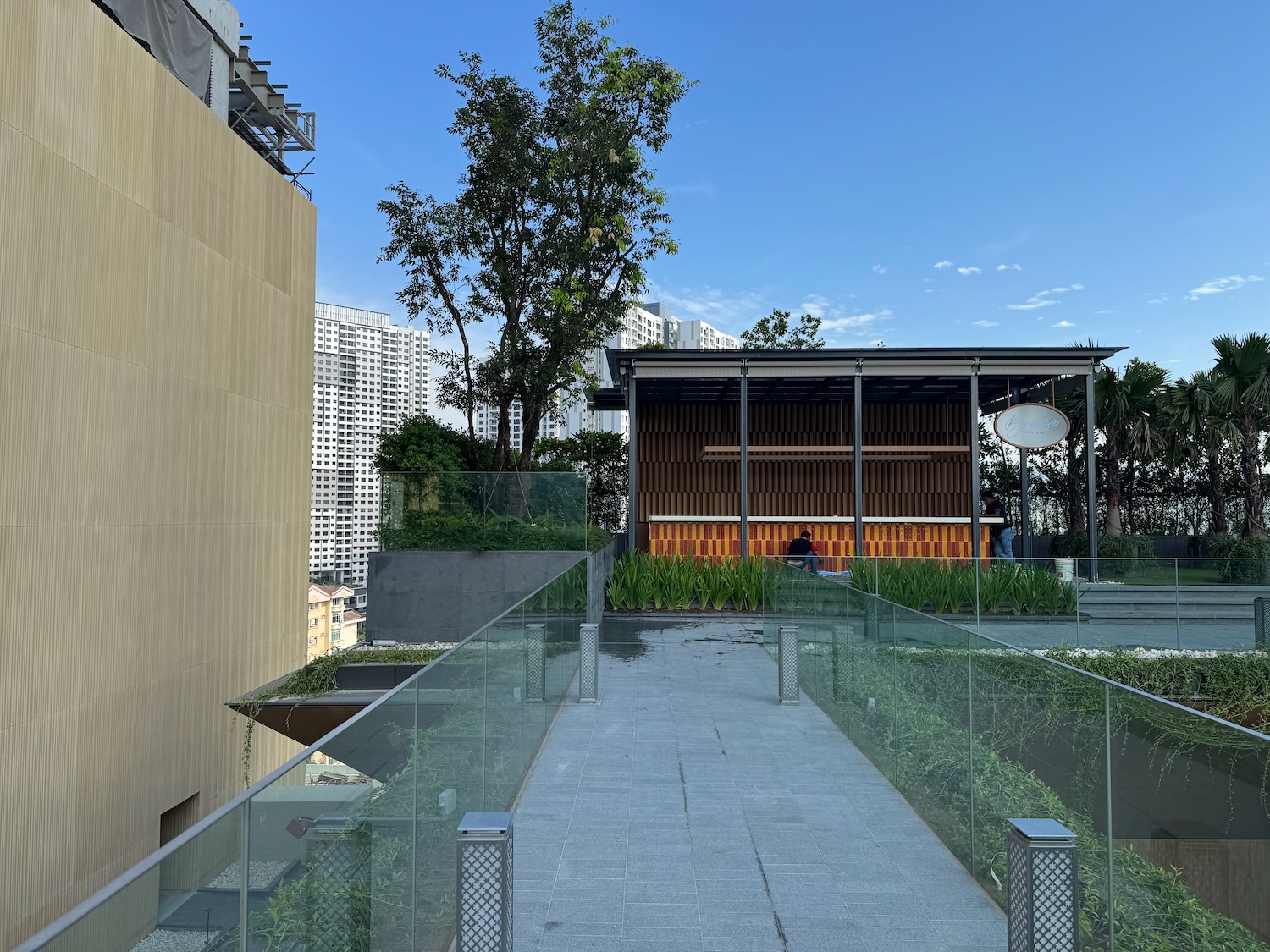 a walkway with glass railings and trees in the background
