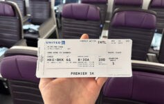 a hand holding a ticket in front of chairs