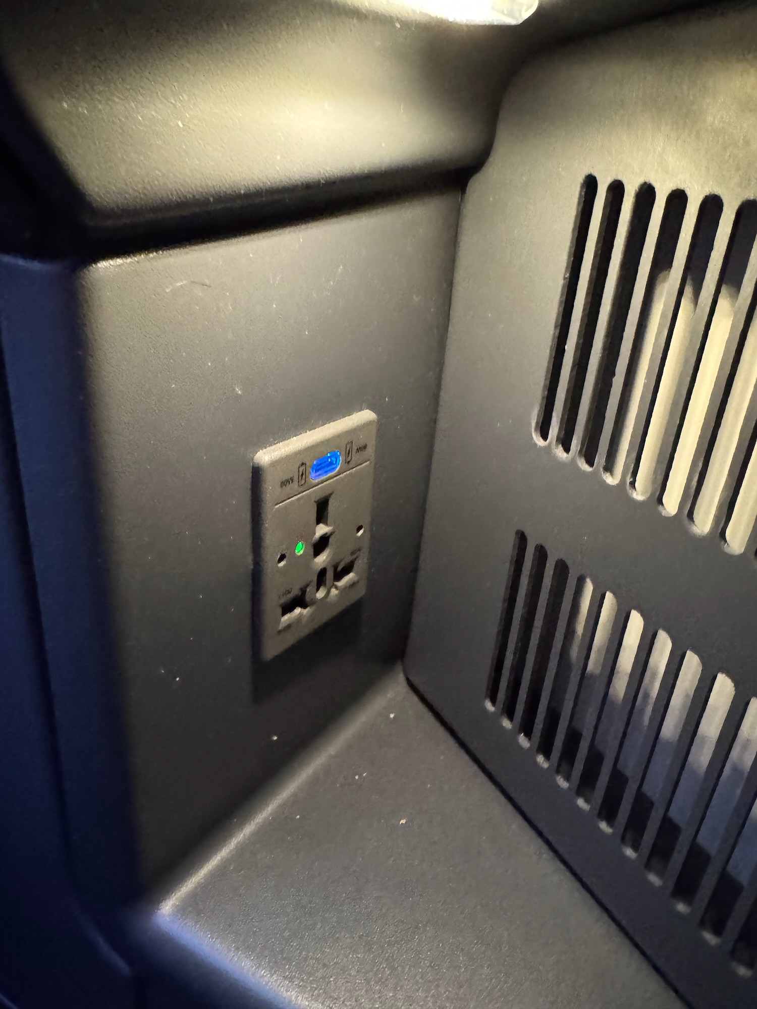 a black wall with a power outlet and vent