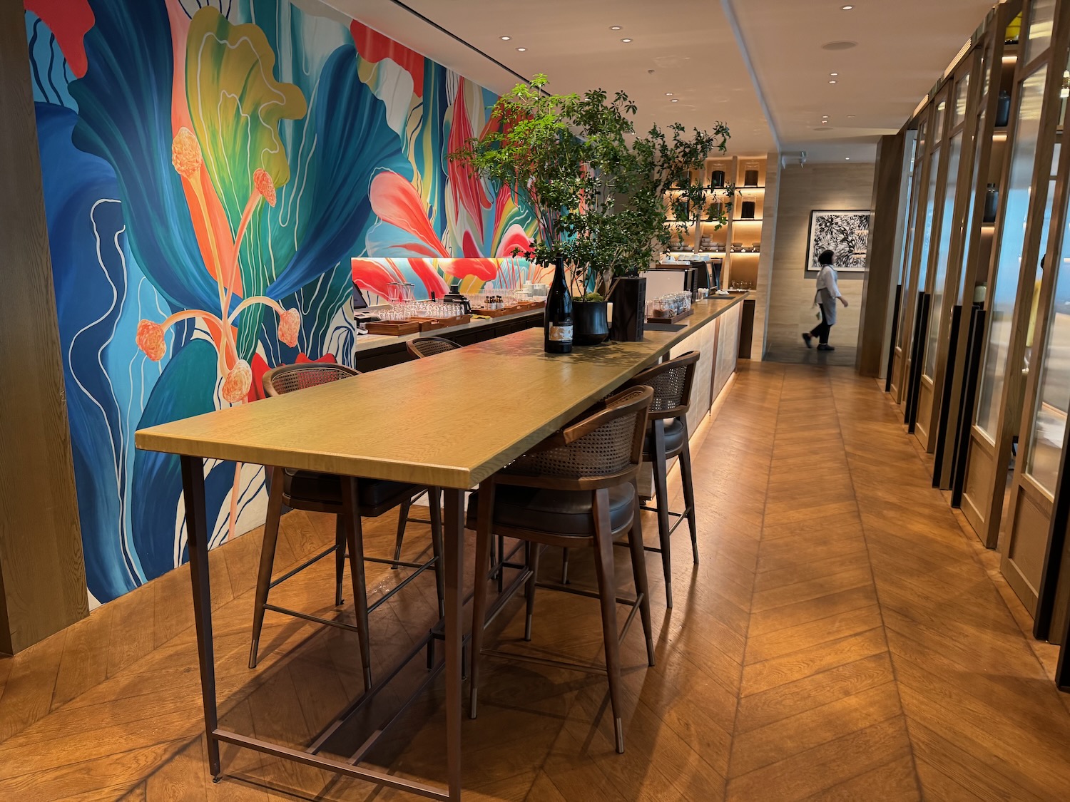 a long table with chairs and a plant in front of a colorful wall