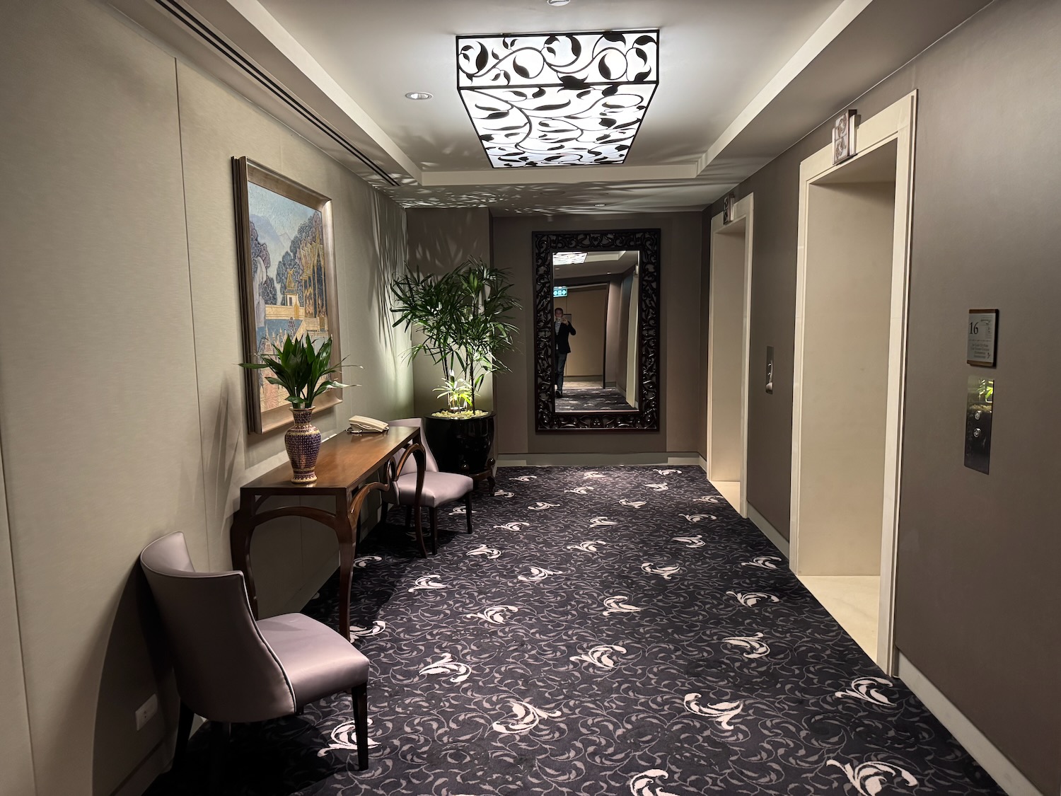 a hallway with a mirror and chairs