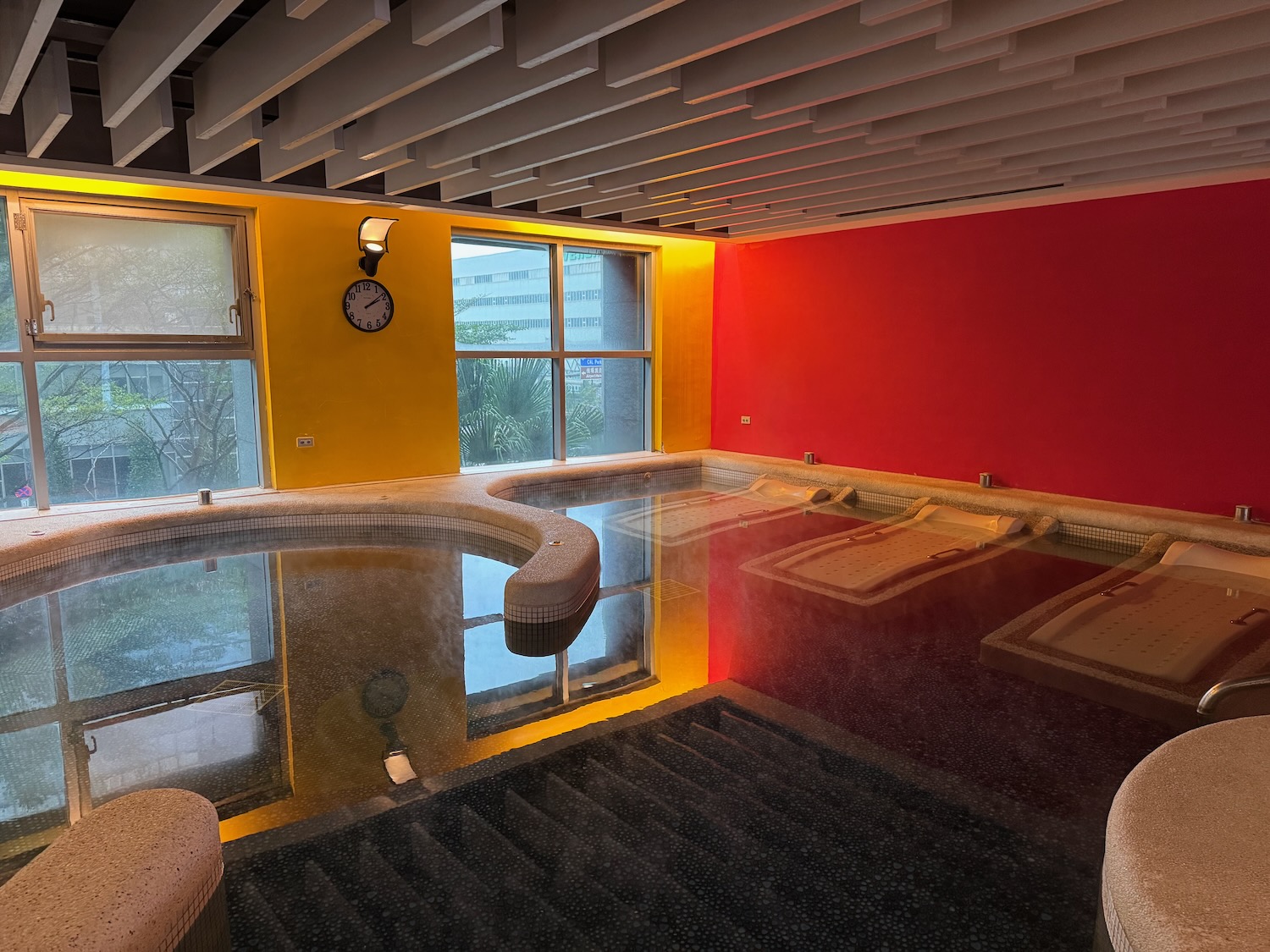 a indoor pool with a round tub and a clock