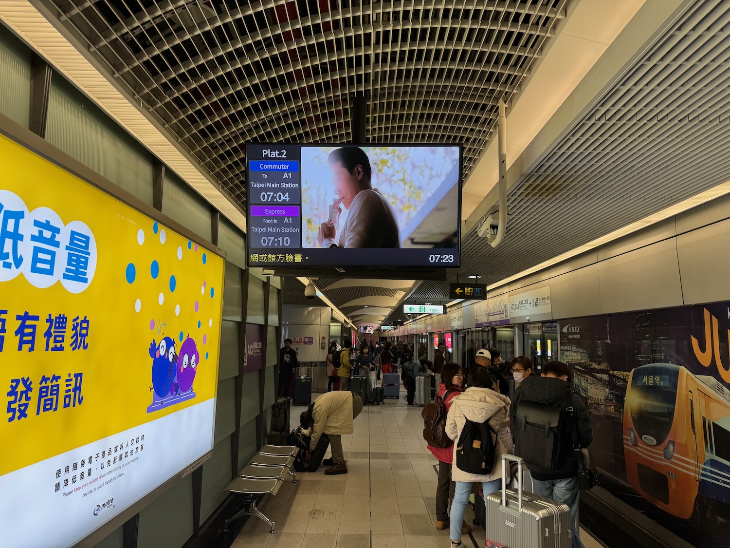 a group of people in a hallway with a television screen