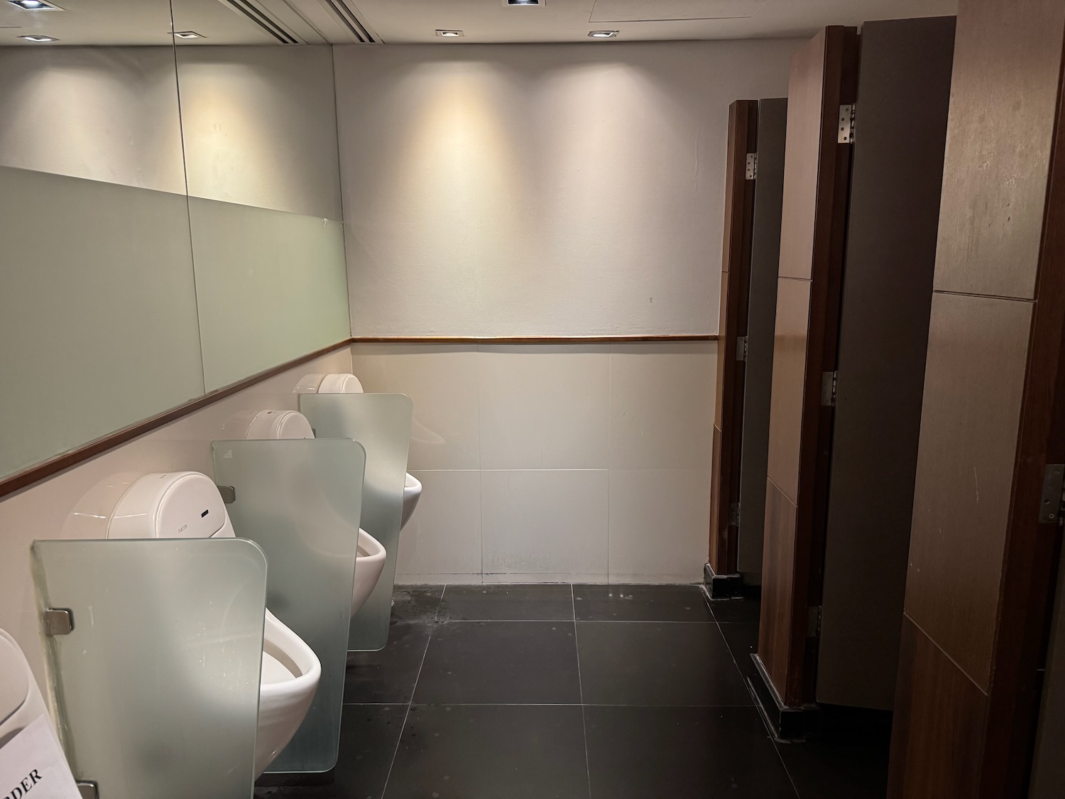 a bathroom with urinals and a wall