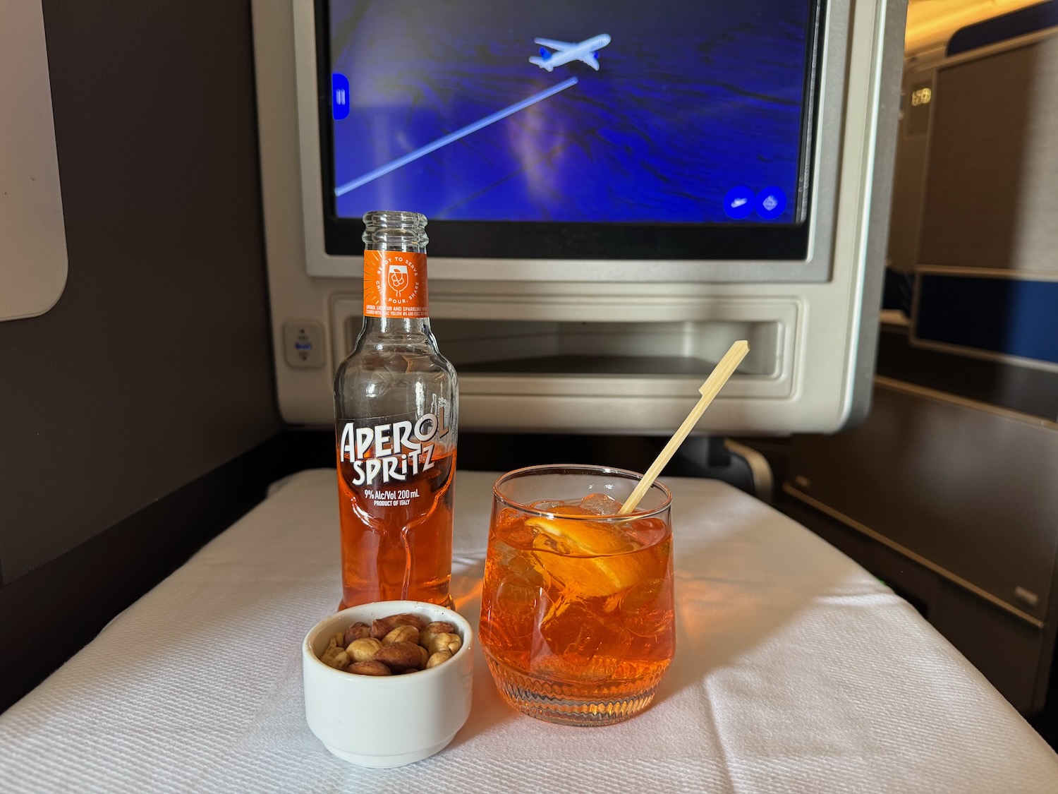 a glass of orange liquid next to a bowl of nuts and a bowl of orange liquid