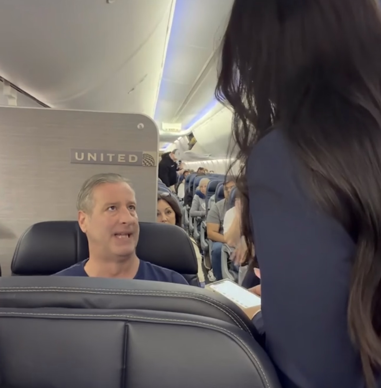 a woman talking to a man in an airplane