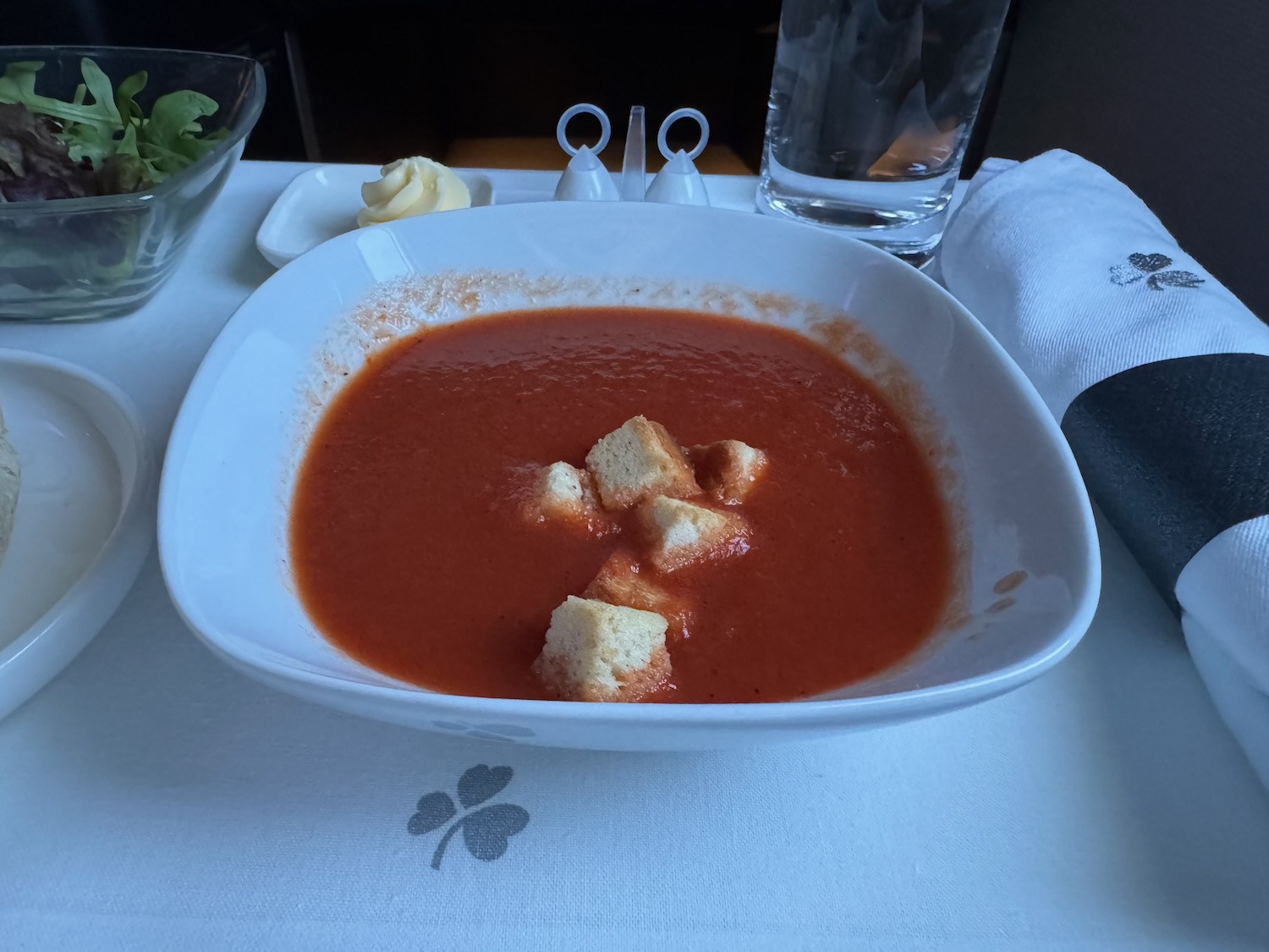 a bowl of tomato soup with croutons on a table