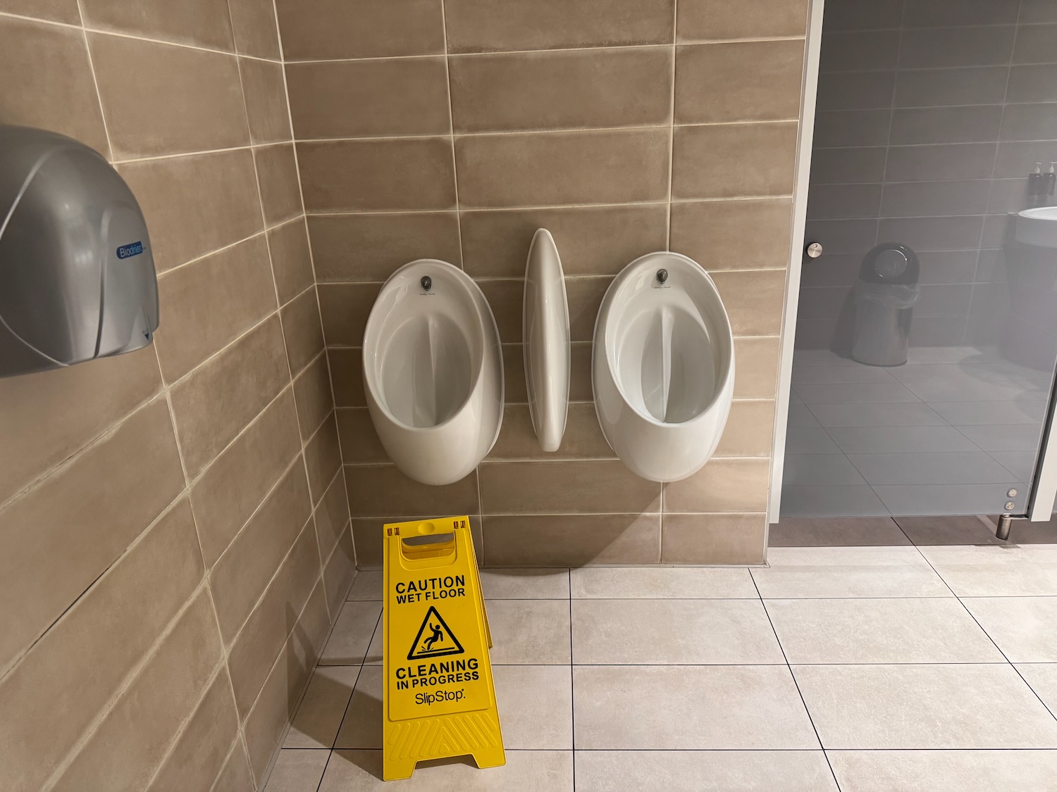 a yellow sign next to urinals