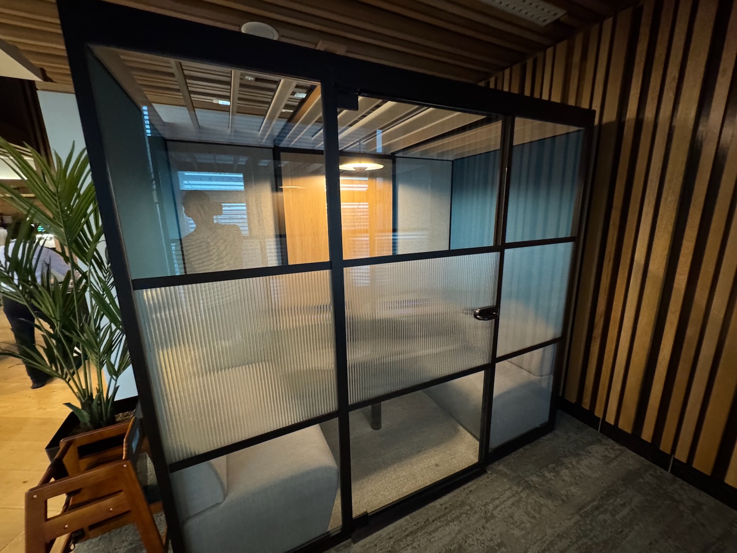 a glass room with a white couch and a plant