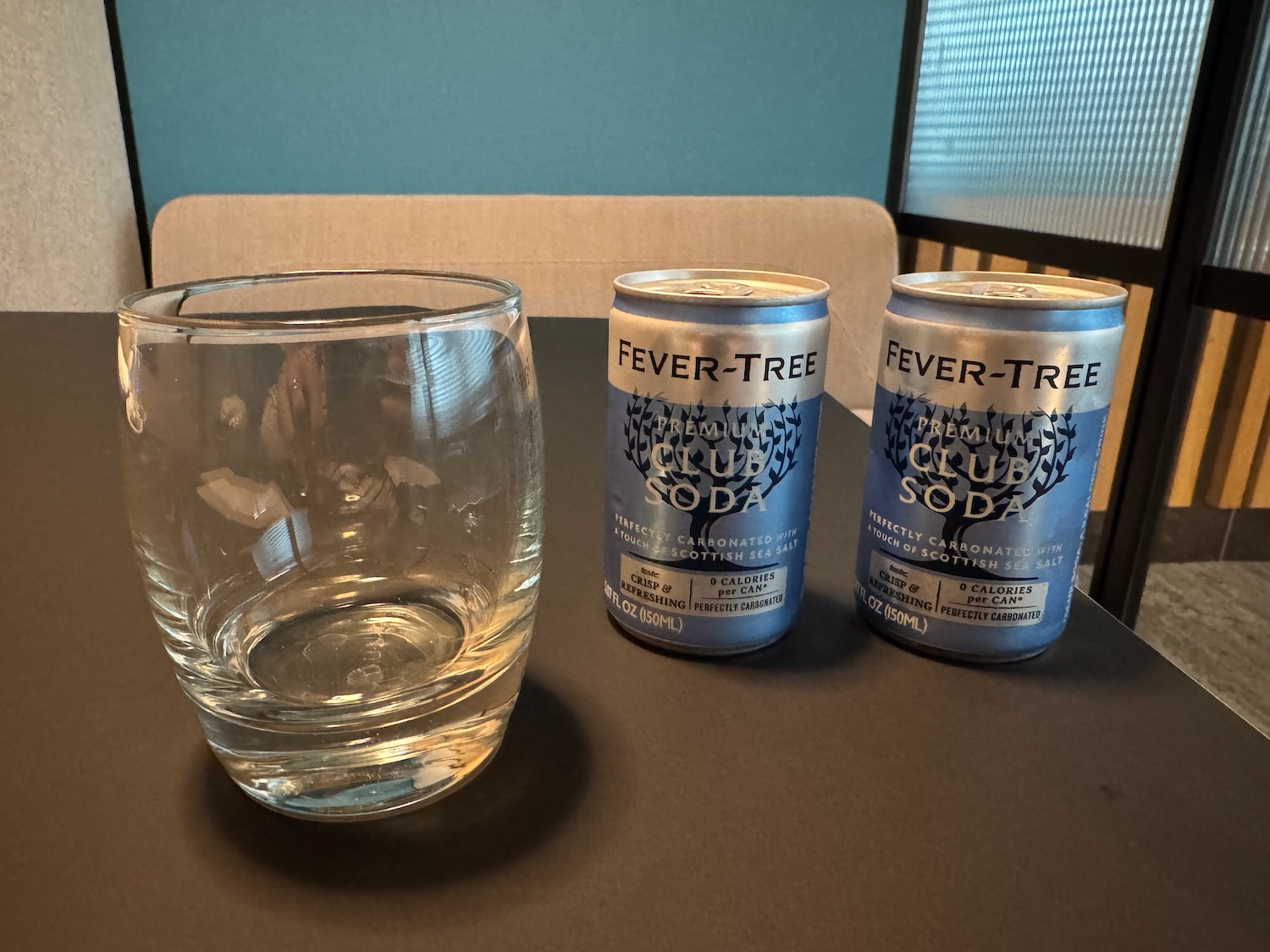 two cans of soda and a glass on a table