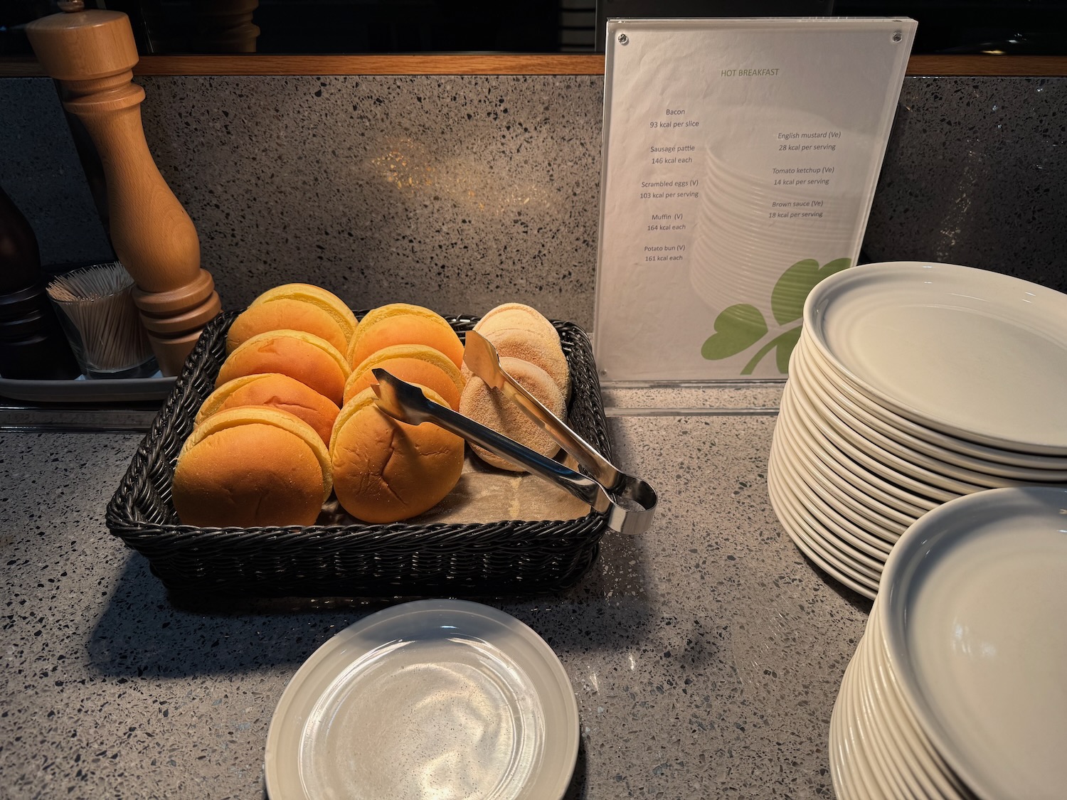 a basket of bread rolls and tongs