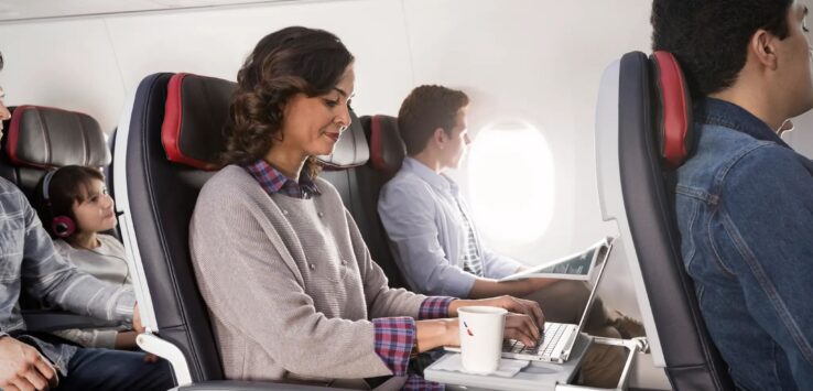 a woman sitting in an airplane with a laptop