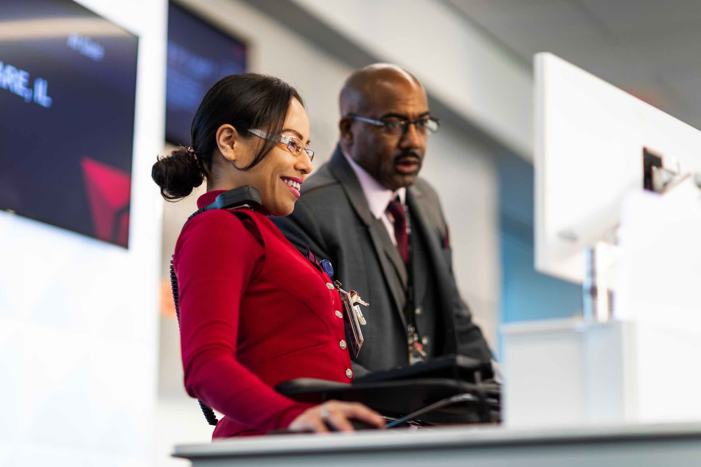 a woman in a red dress sitting at a desk with a man in a suit