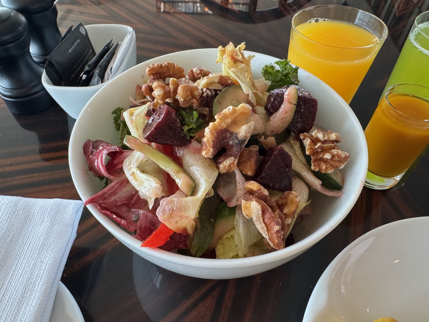 a bowl of salad with orange juice and a glass of orange juice