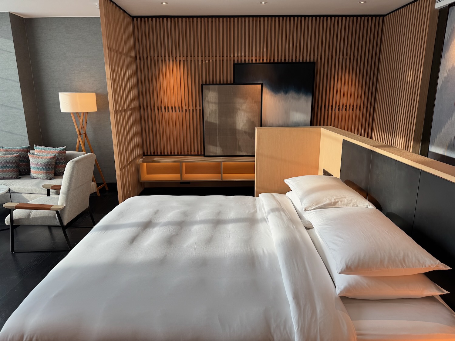 a bed with white sheets and pillows in a room with a wood paneled wall