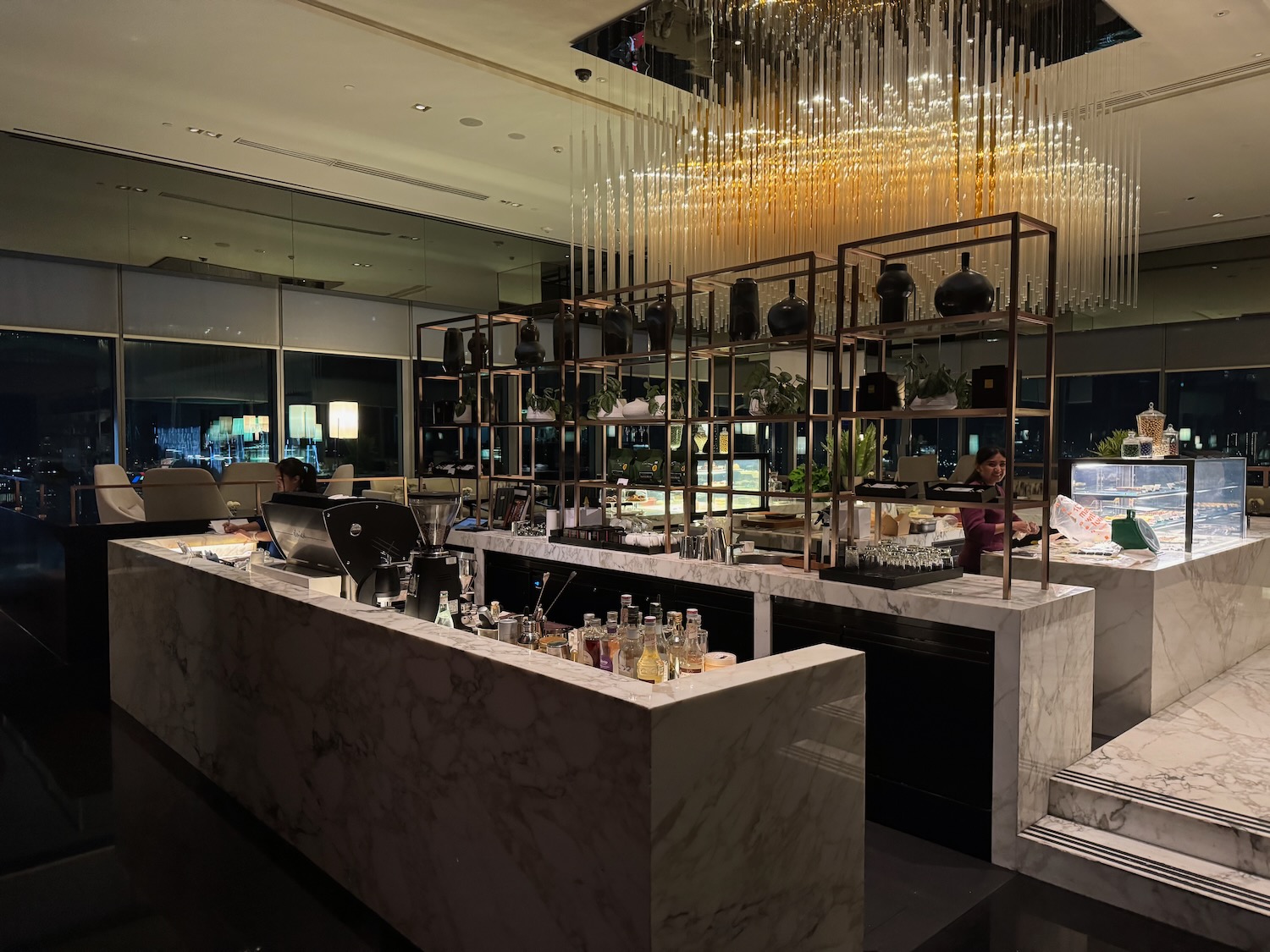 a bar with a chandelier and a couple of people