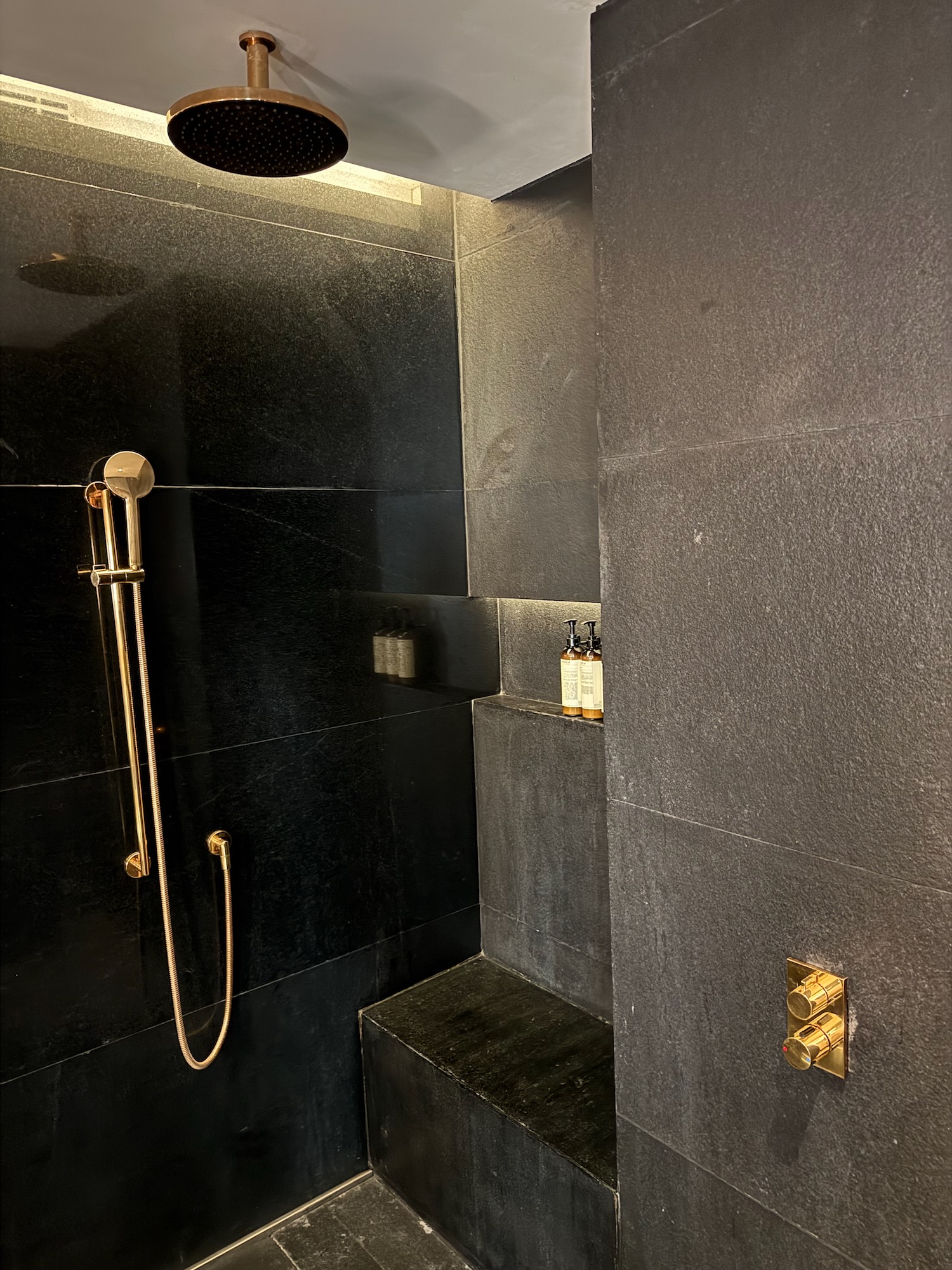 a shower with a black tile wall