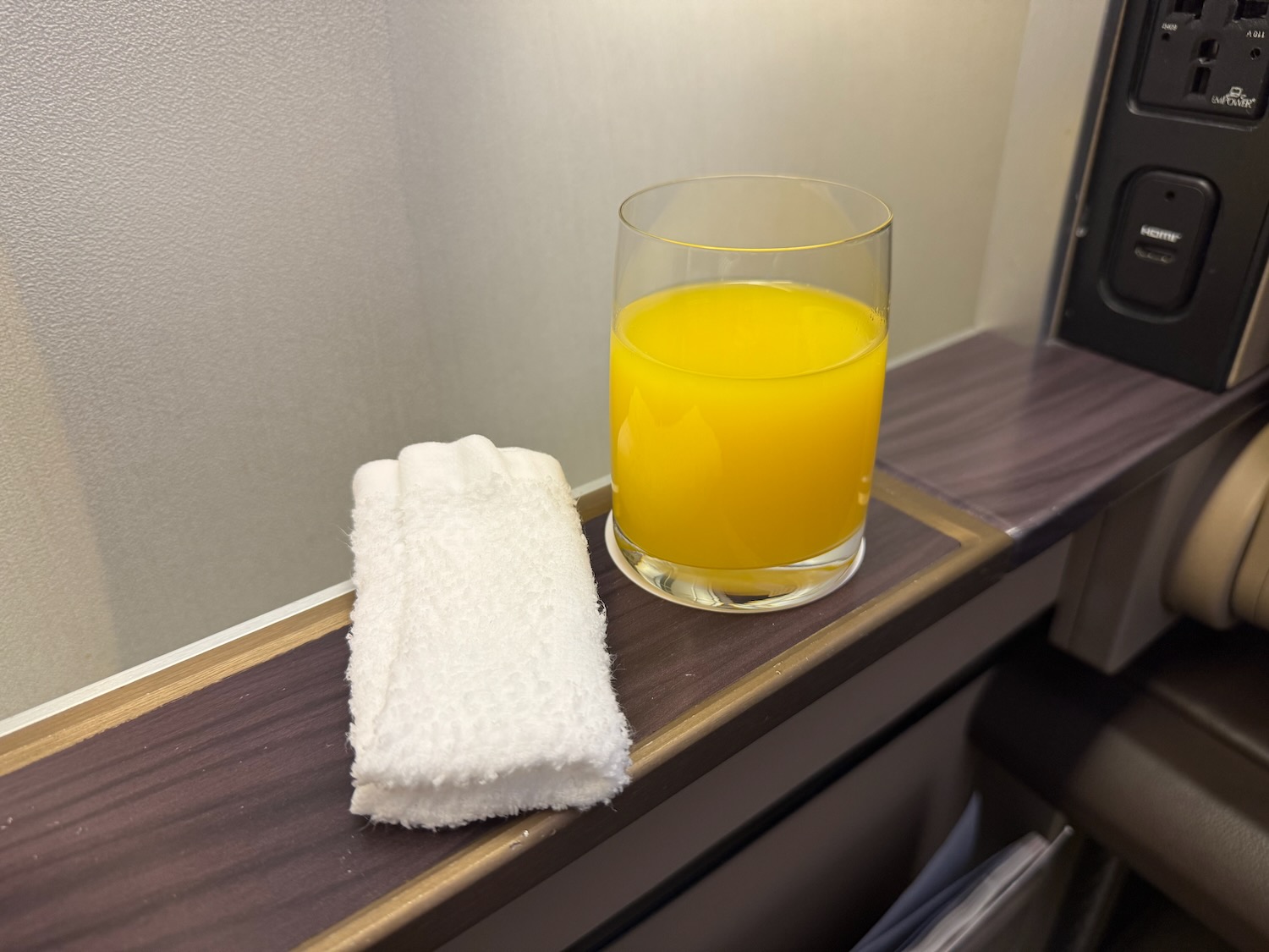 a glass of orange juice and a towel on a shelf