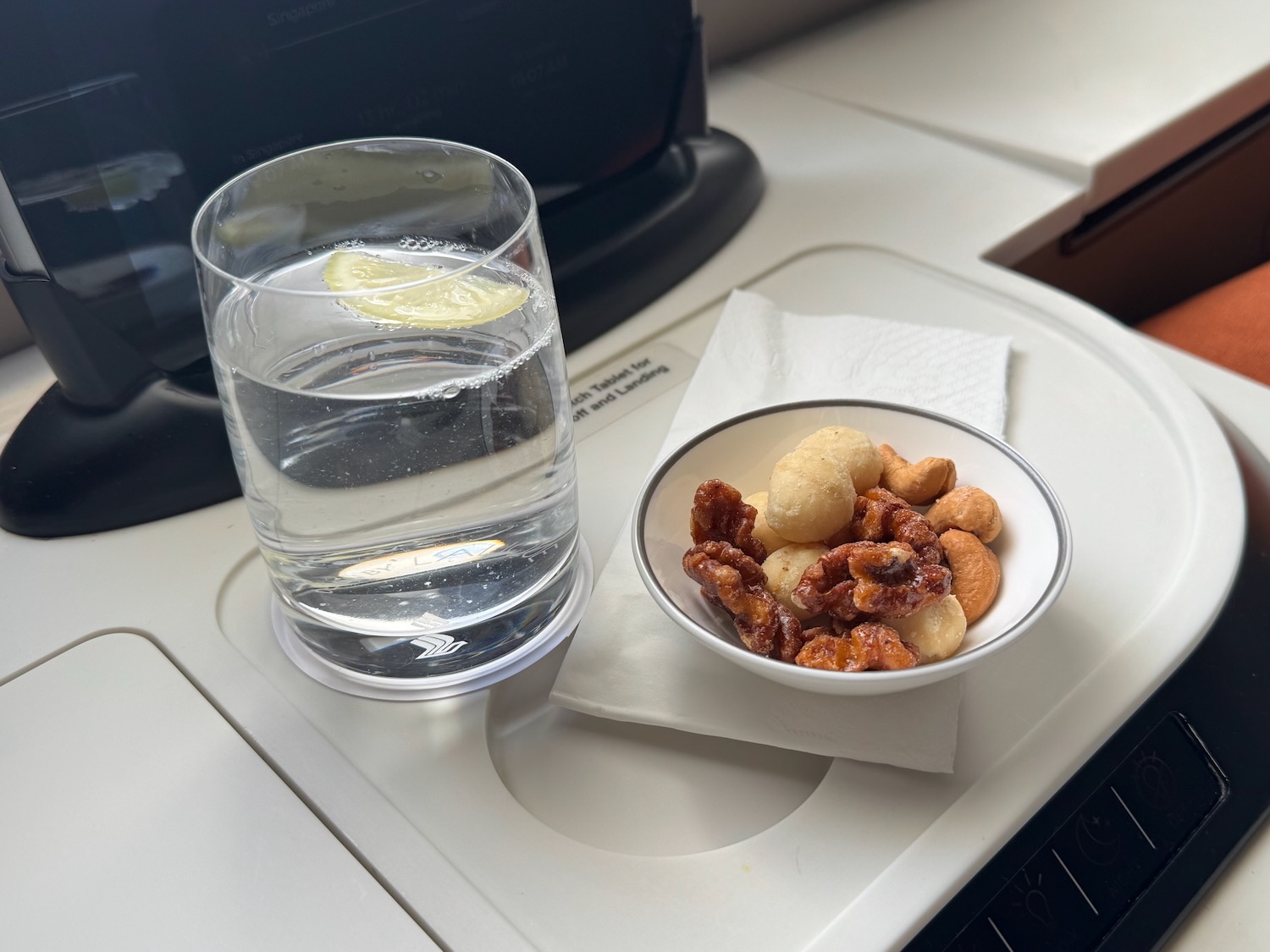 a bowl of nuts and a glass of water on a tray